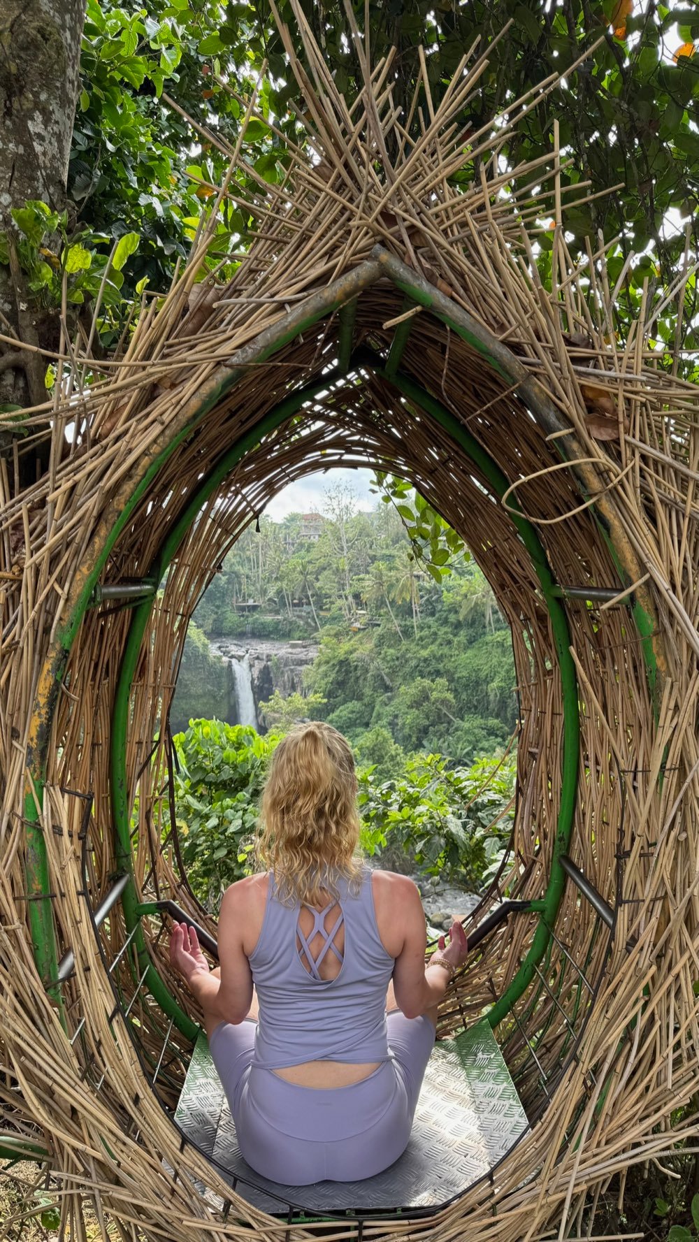 Andrea in meditativer Haltung inmitten üppiger Natur, mit Blick auf einen Wasserfall